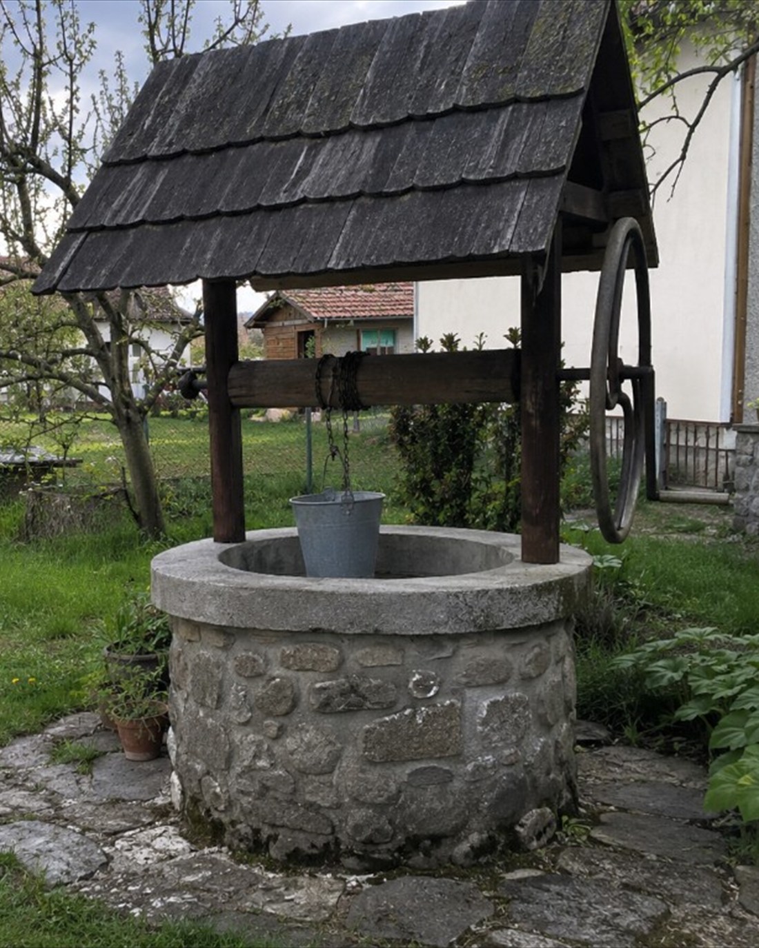 Zhotovená vrtaná studna s kamenným pažením a dřevěnou stříškou